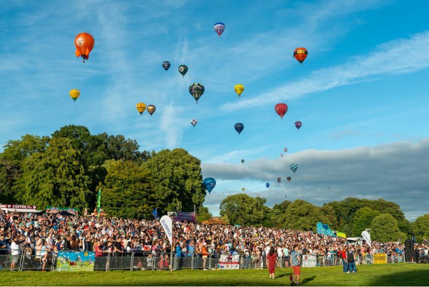 crowds of people watching hot air balloons in the sky